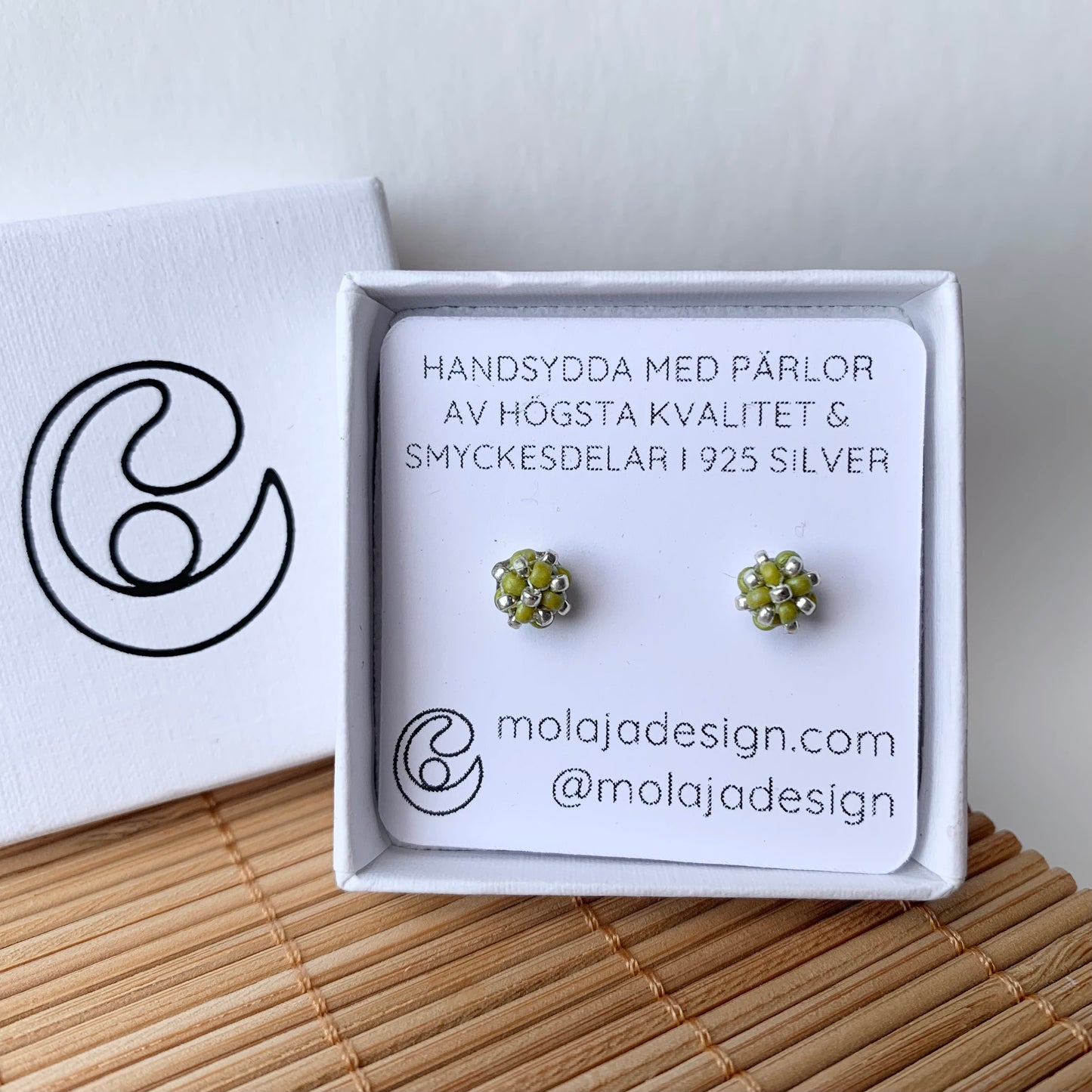 Ljus grön studs i smyckesask med text från MoLaja Design.