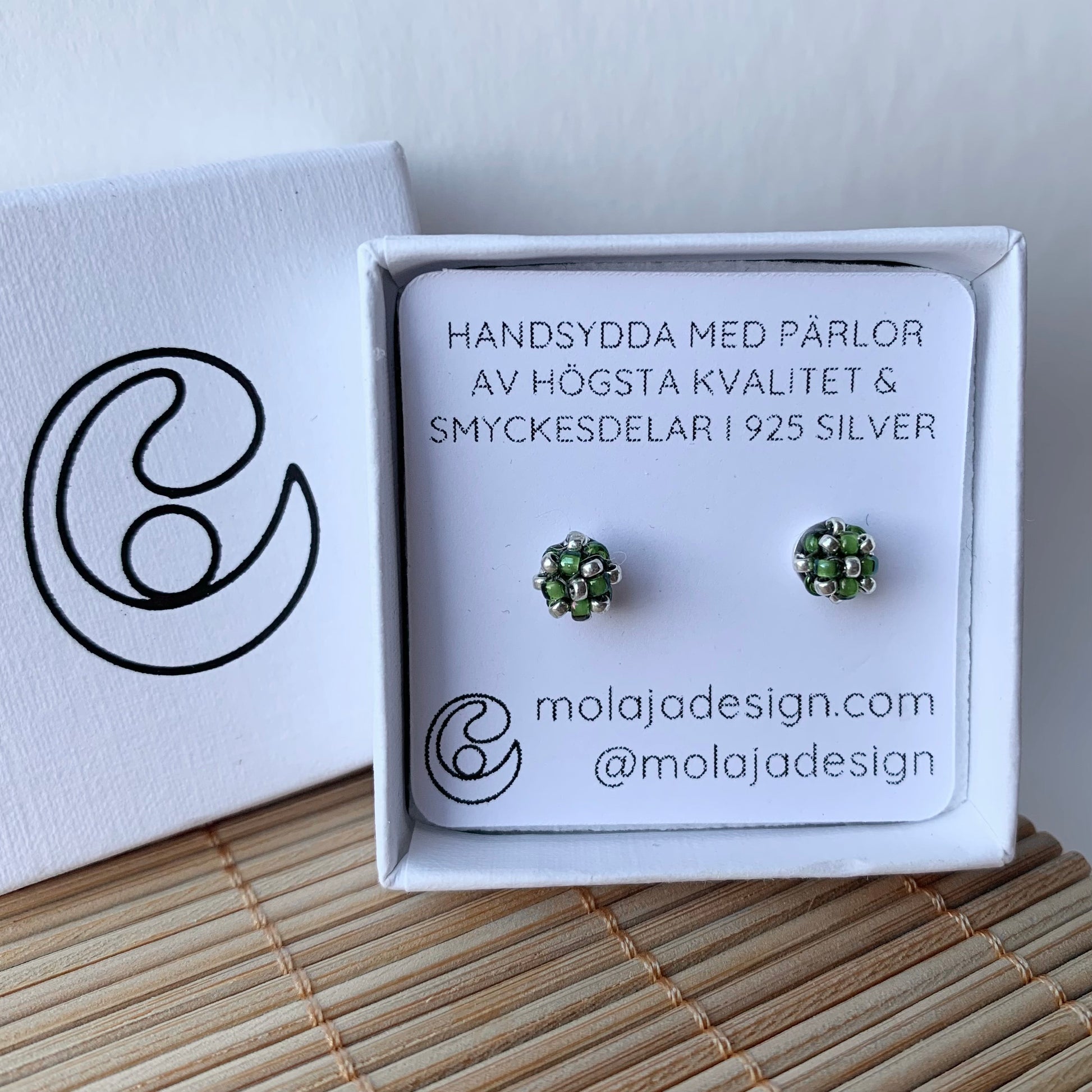 Transparent grön studs i smyckesask med text från MoLaja Design.