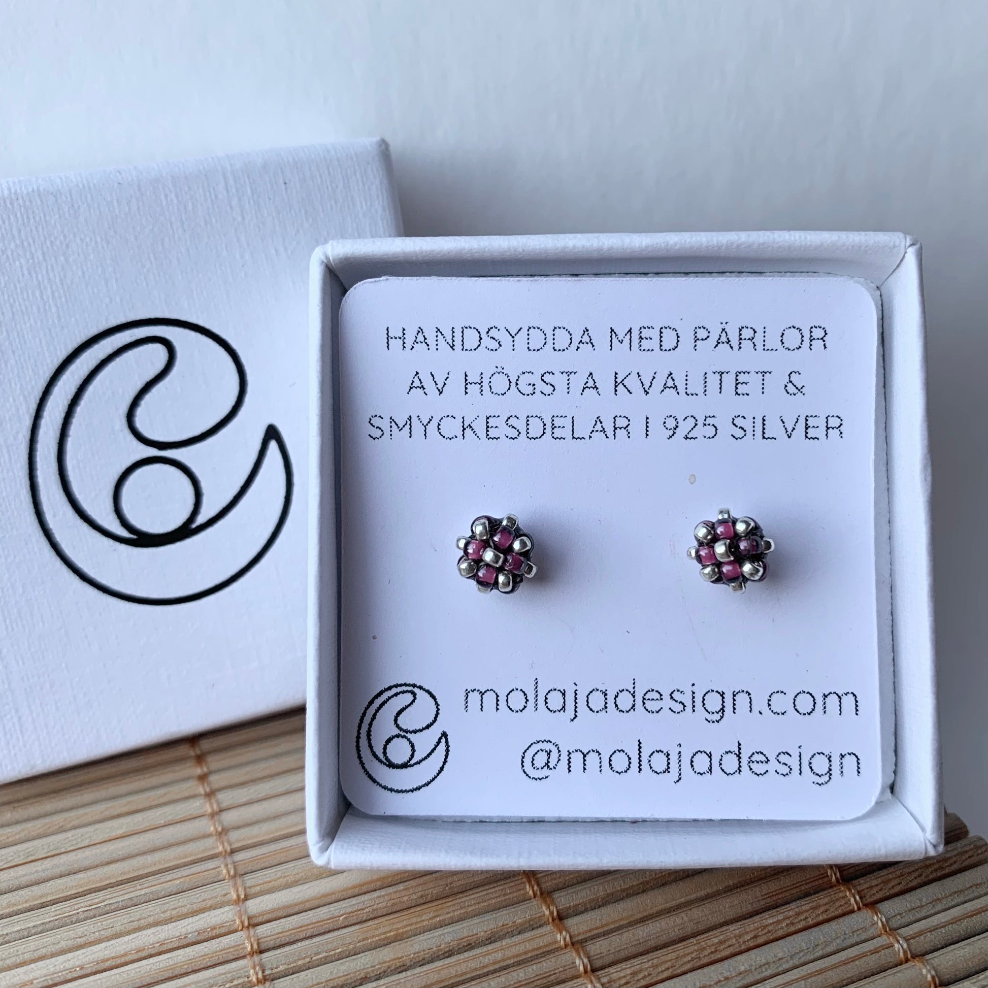 Transparent mörk lila studs i smyckesask med text från MoLaja Design.
